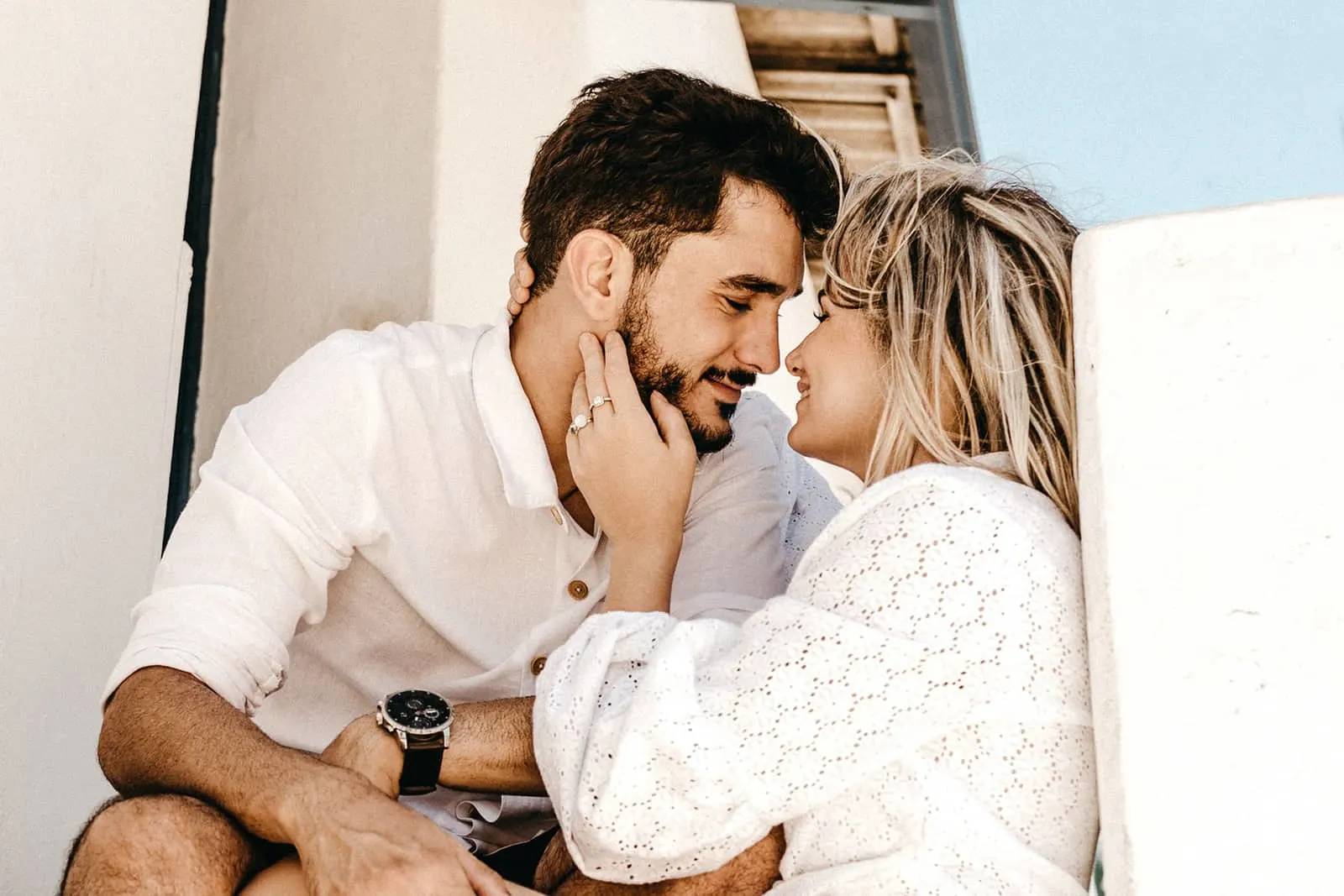 Eine lächelnde Frau, die das Gesicht ihres Mannes berührt, will sich küssen