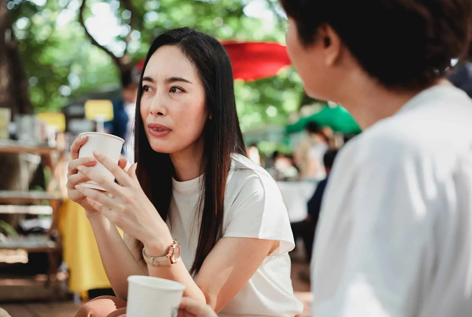 eine nachdenkliche Frau, die mit einer Freundin spricht, während sie zusammen Kaffee trinkt