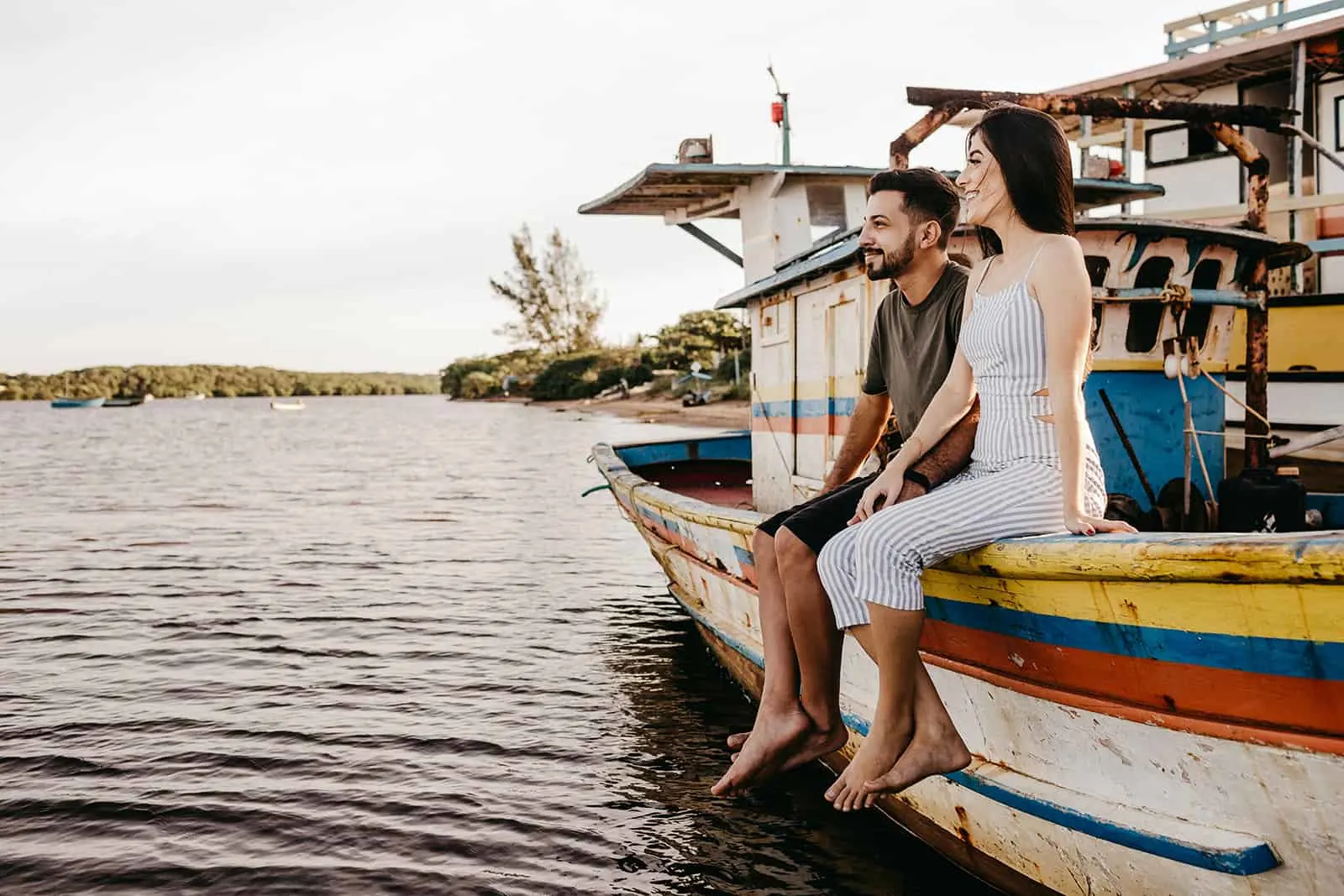 glückliches Paar, das auf dem Boot sitzt und Hände hält
