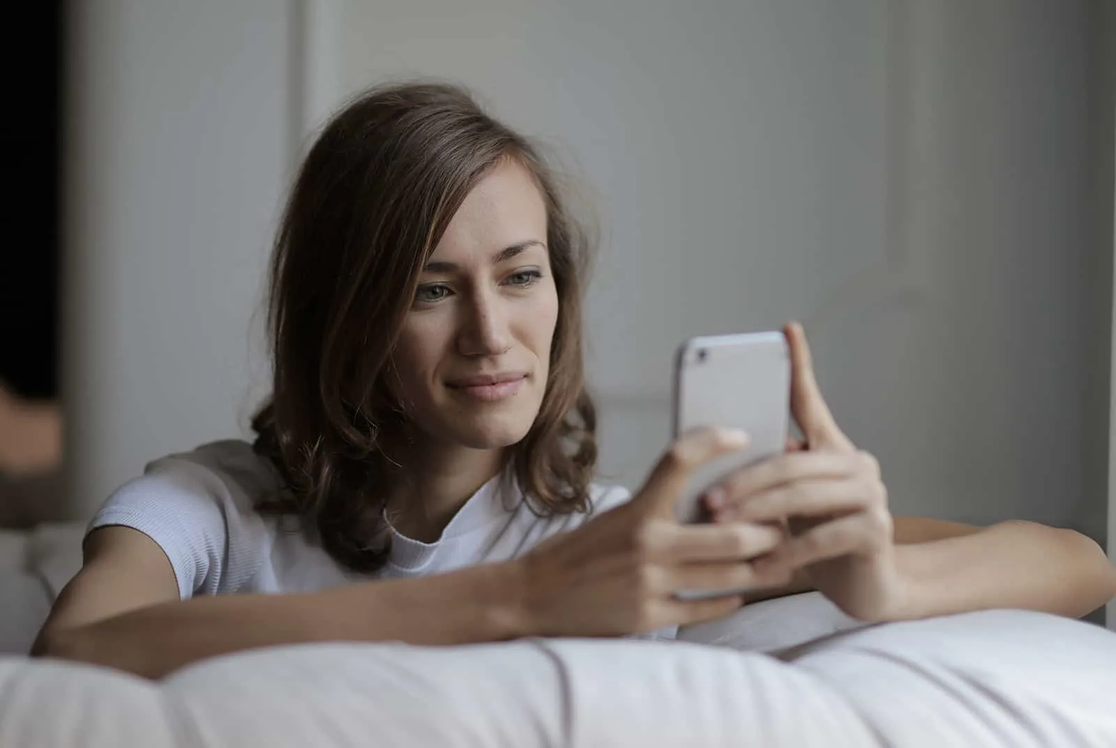 lächelnde Frau SMS auf Smartphone sitzen auf der Couch