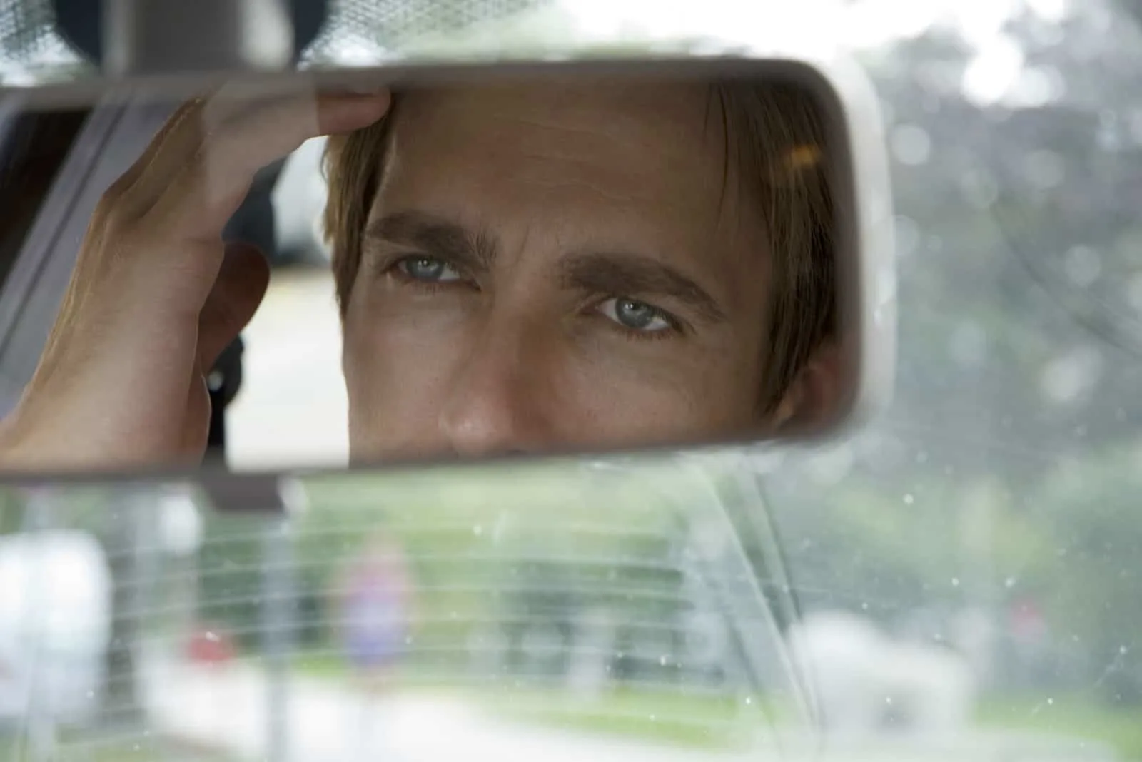 Ein gutaussehender Mann schaut im Auto in den Spiegel