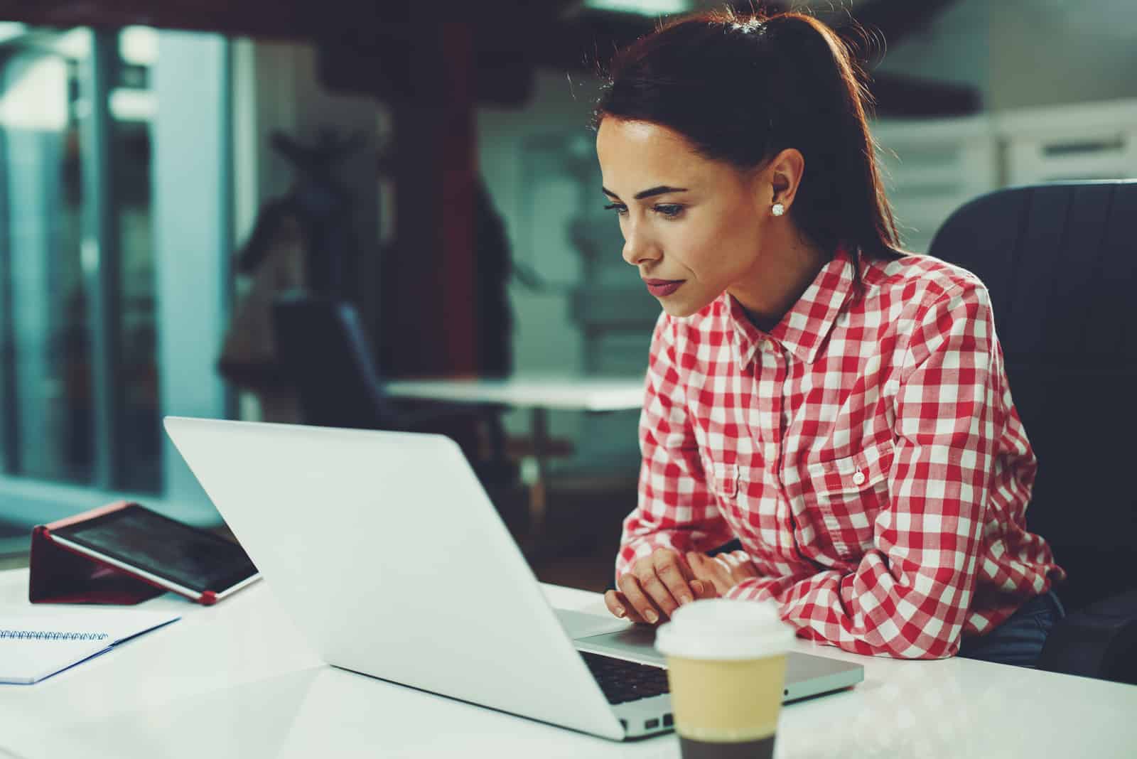Junge Frau, die am Laptop im Büro arbeitet