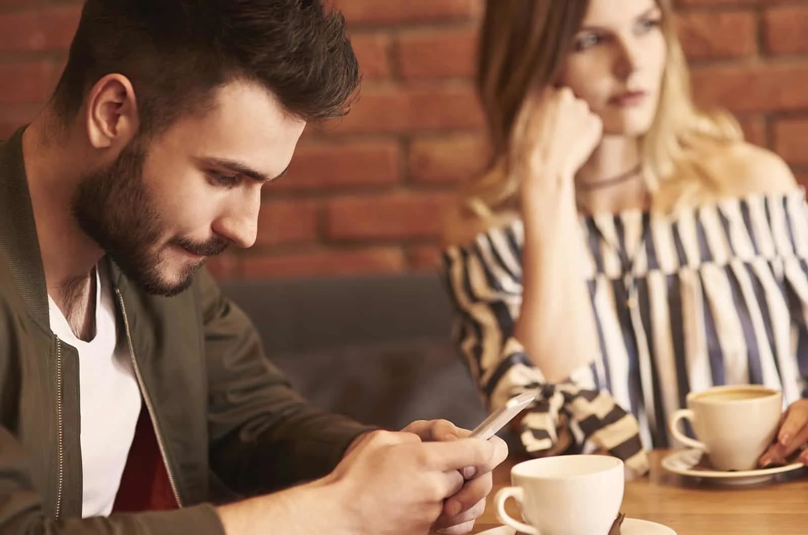 Mann mit Smartphone beim Sitzen mit einer Frau im Café