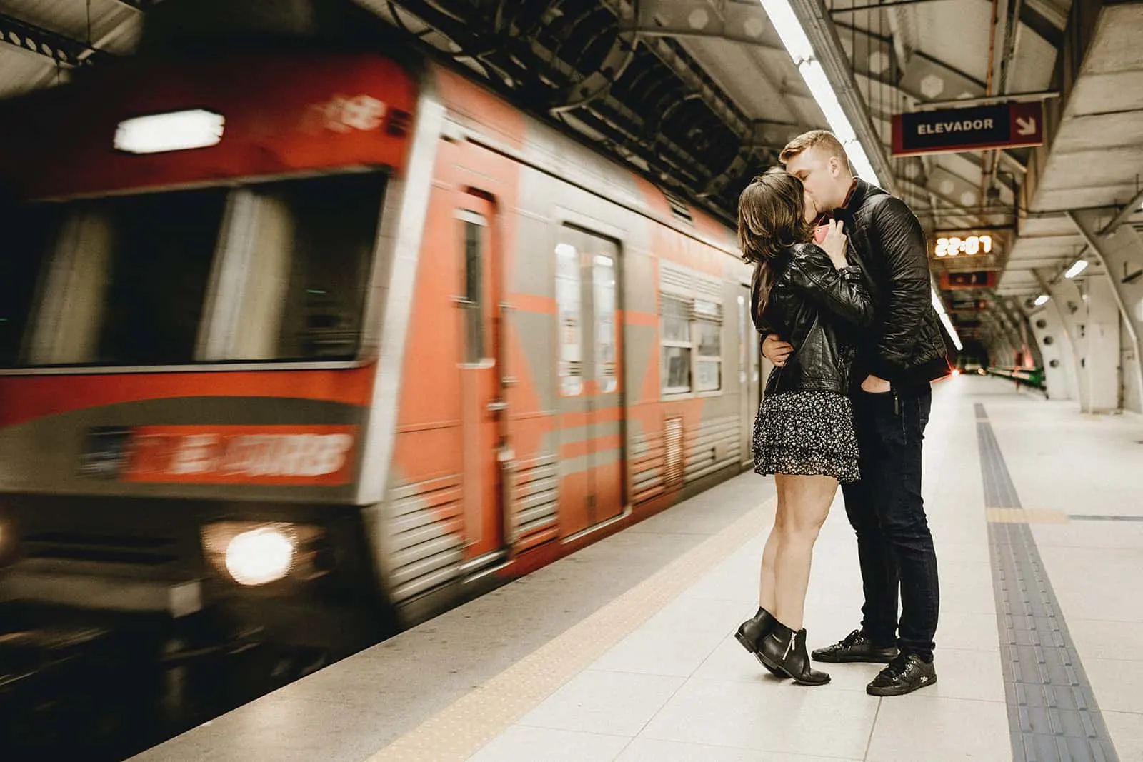 Paar küsst sich in einer U-Bahn, während der Zug neben ihnen vorbeifährt