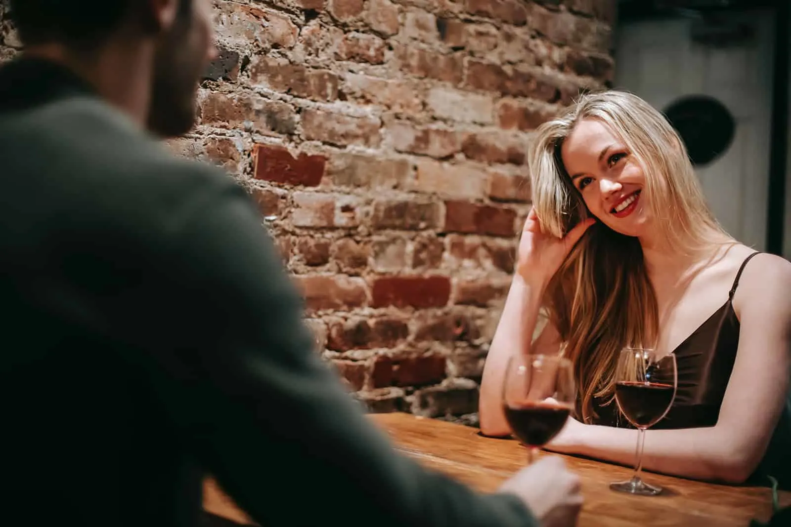 attraktive Frau, die mit einem Mann in einem Restaurant sitzt und zusammen Wein trinkt