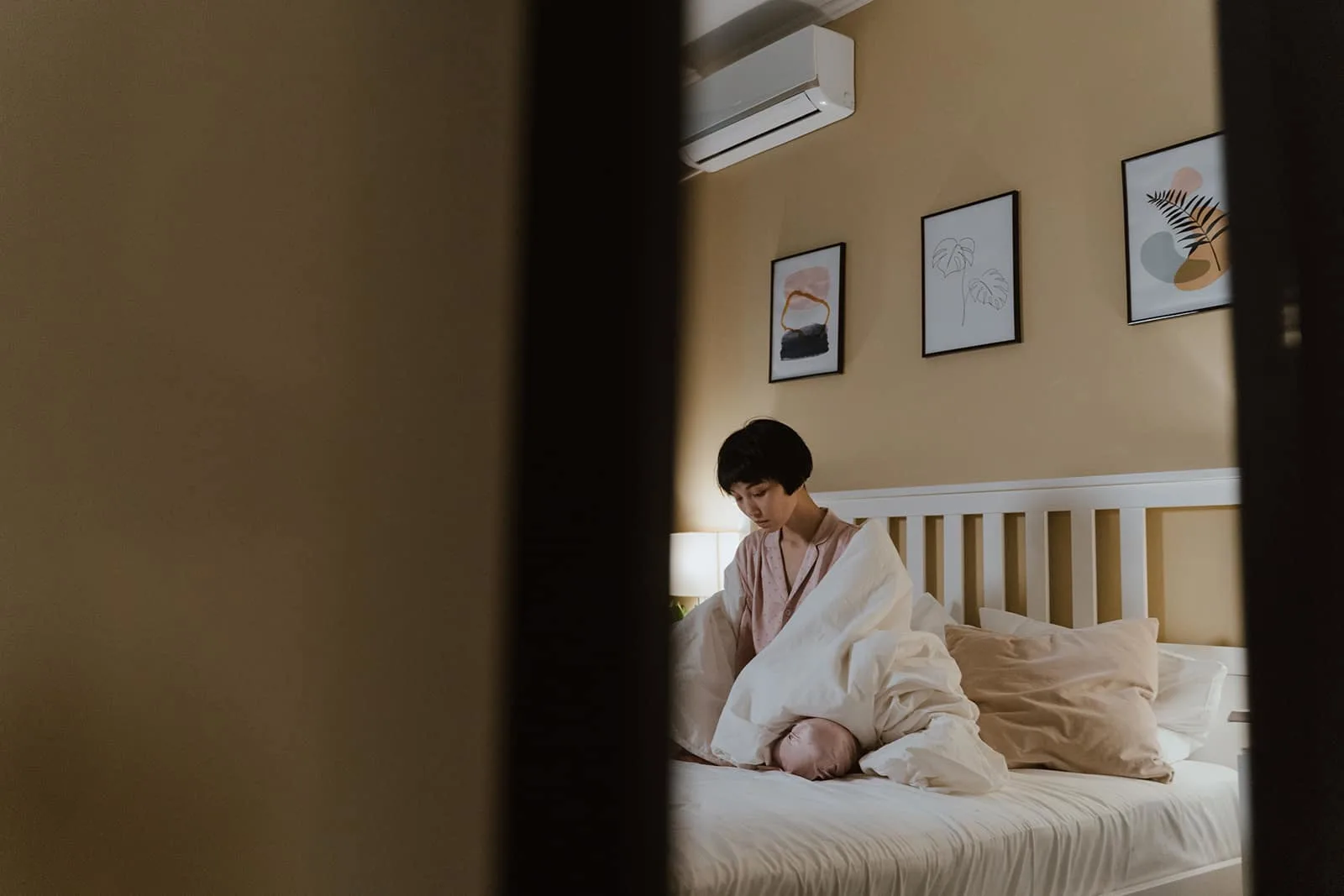 depressive Frau sitzt auf dem Bett mit Decke bedeckt