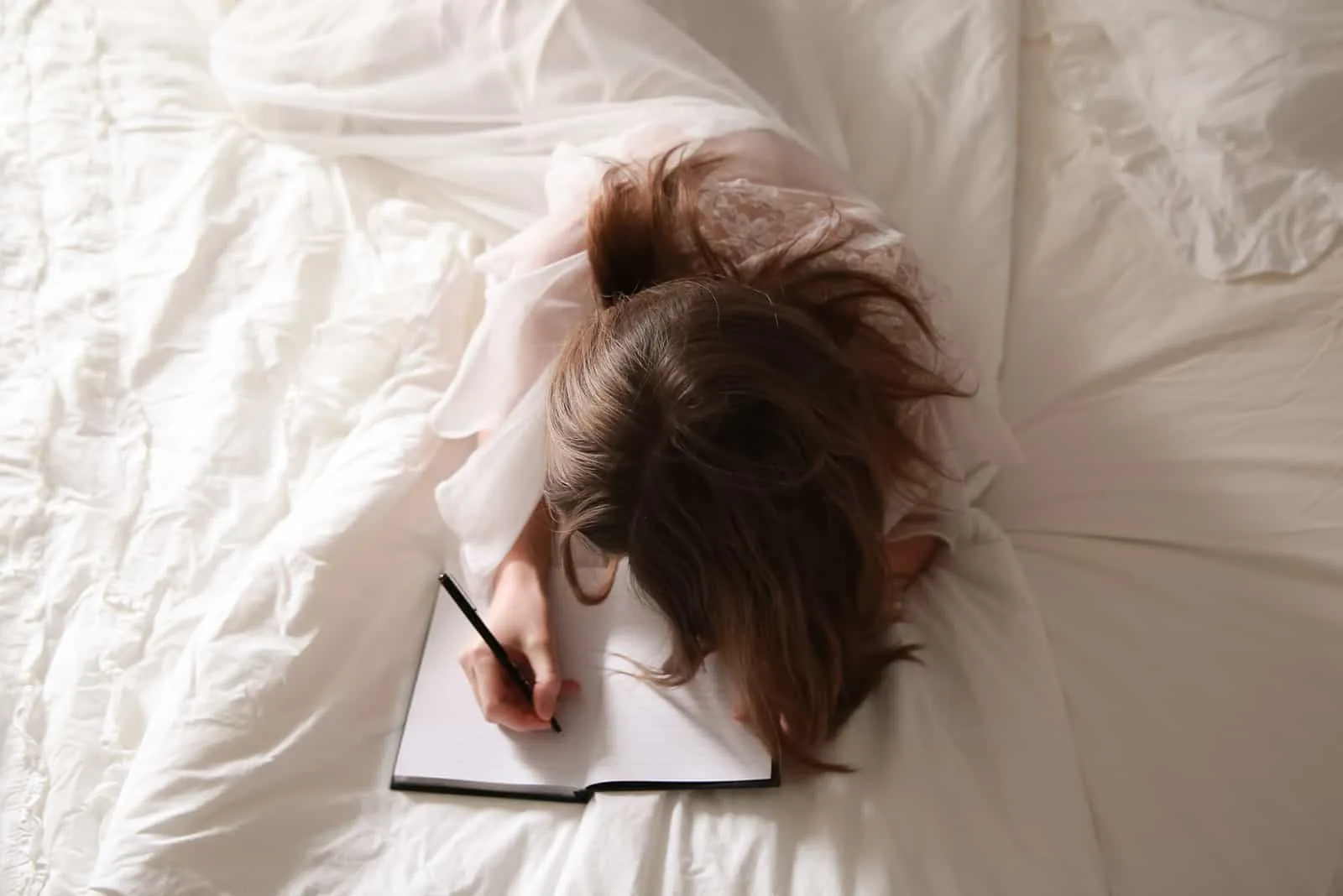 eine Frau, die einen Liebesbrief schreibt, während sie auf dem Bett liegt