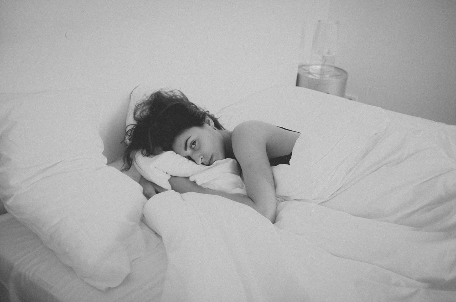 eine Frau, die im Bett liegt und ein Kissen umarmt