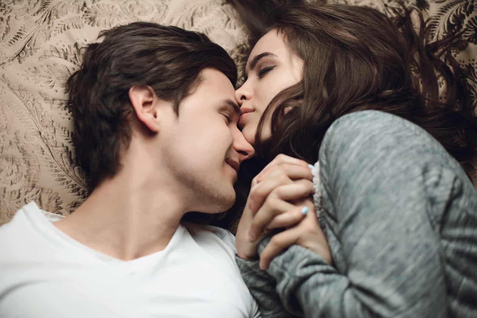 schönes brünettes Mädchen und Kerl, die im Bett liegen