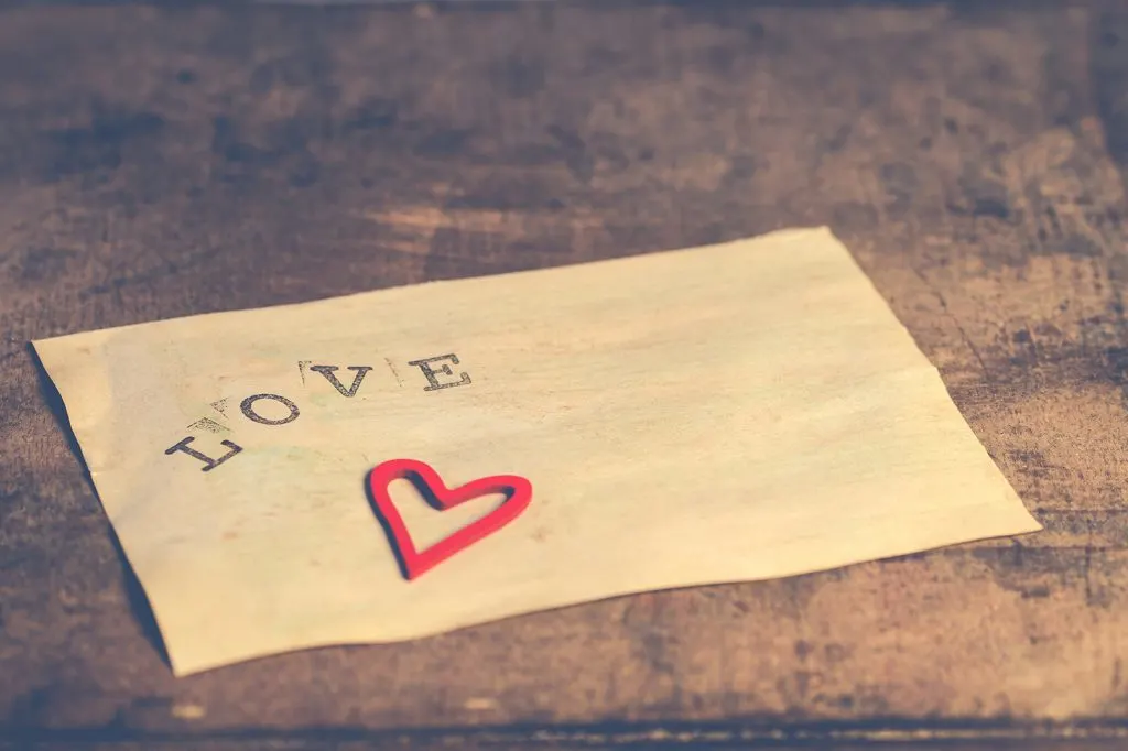 weißes Papier mit dem Wort Liebe aufgedruckt und papierförmiges Herz
