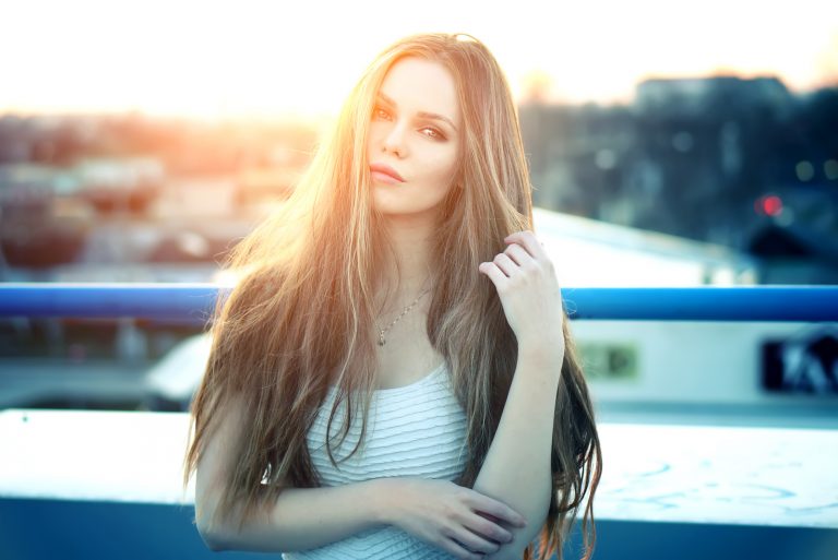 Eine schöne Blondine steht bei Sonnenuntergang auf einer Brücke