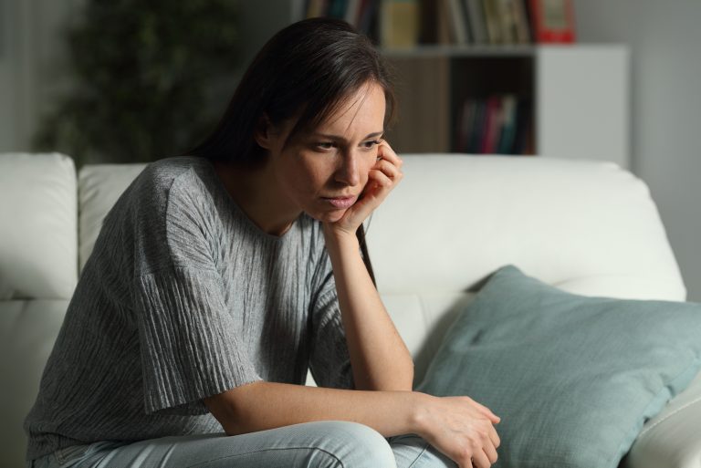 nachdenkliche Frau in der Nacht auf einer Couch sitzen