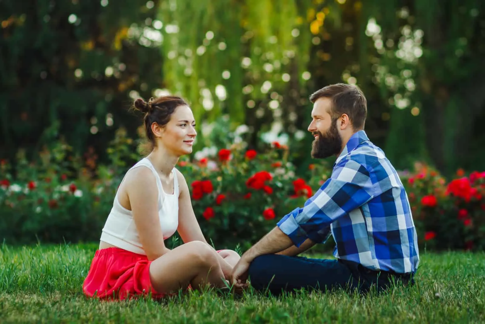 Paar im Freien miteinander reden - auf Gras sitzen
