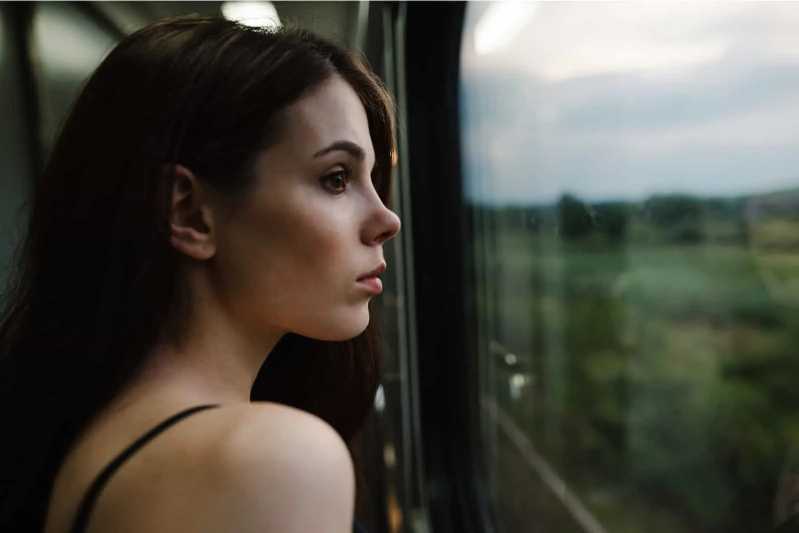 attraktiver weiblicher Zugpassagier, der am Fenster steht