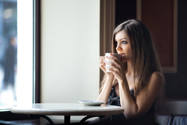 Schöne junge Frau mit einer Tasse Tee in einem Café