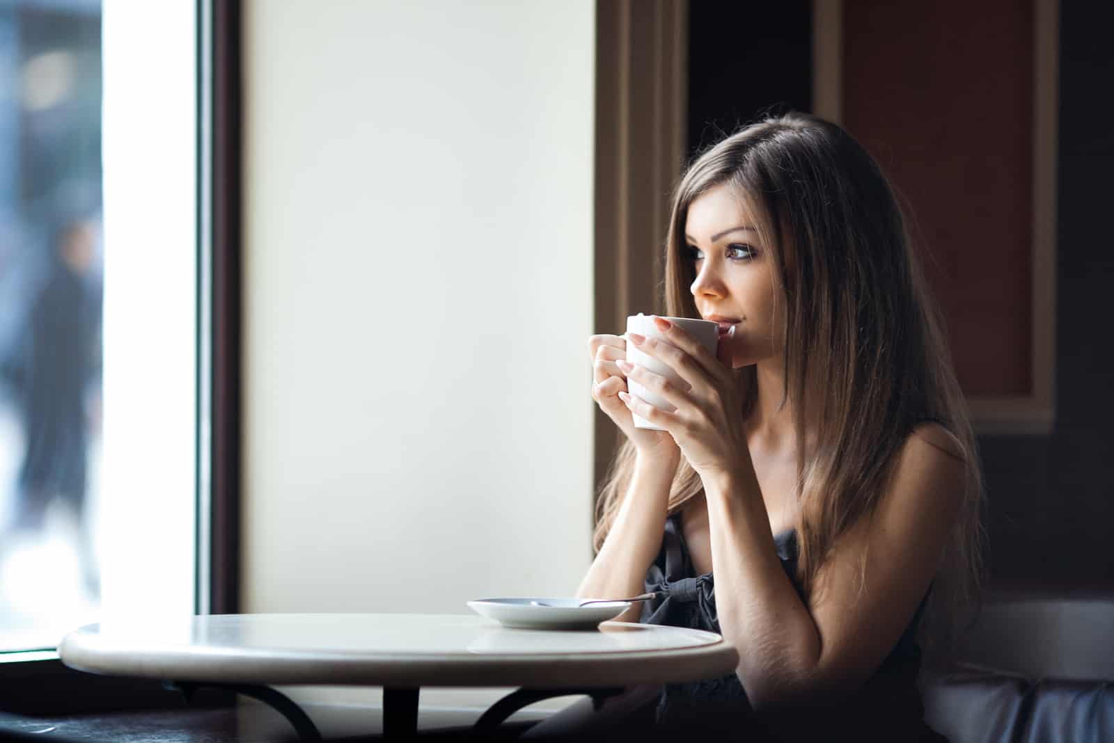 Schöne junge Frau mit einer Tasse Tee in einem Café