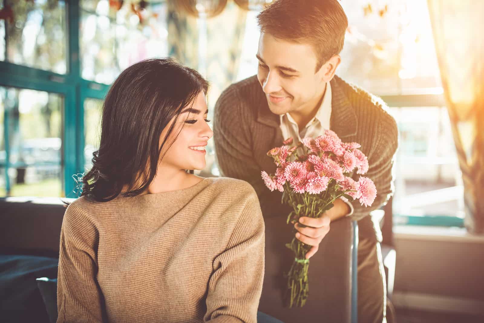 Der glückliche Mann, der im Restaurant Blumen für eine Frau schenkt