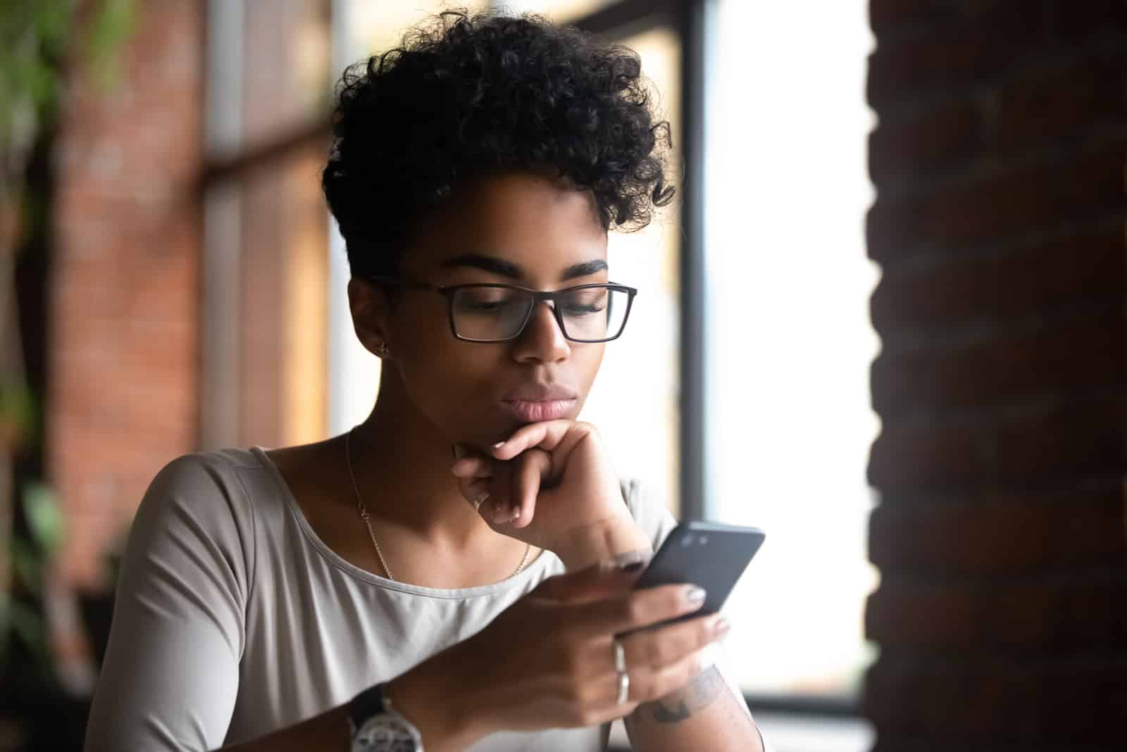 Frau, die Brille hält Telefon hält