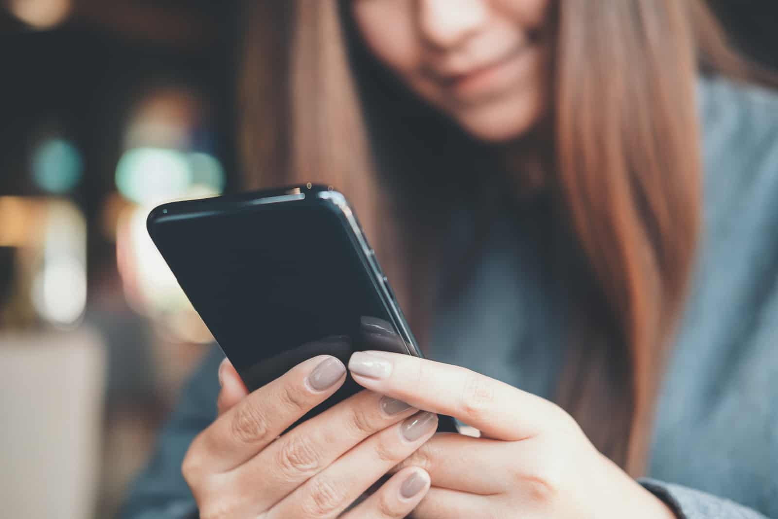 Frau hält, benutzt und schaut Smartphone mit dem Gefühl glücklich