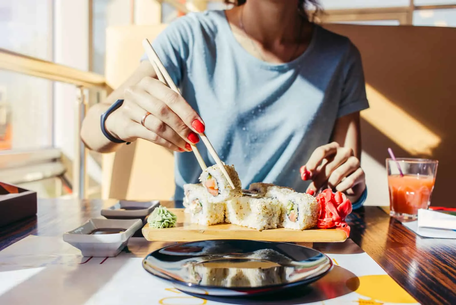 Frau im blauen Hemd isst an einem Sushi-Restaurant