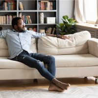 junger Mann sitzen entspannen auf bequemer Couch im Wohnzimmer