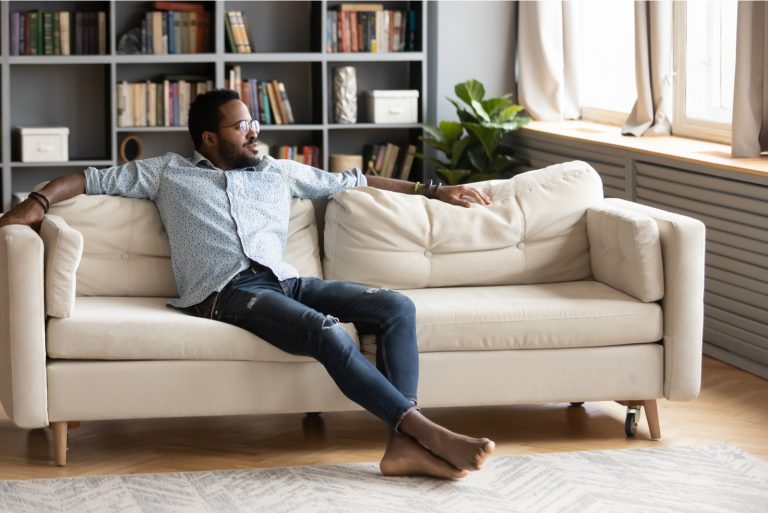 junger Mann sitzen entspannen auf bequemer Couch im Wohnzimmer