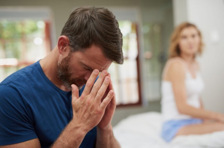 trauriger Mann mit Frau sitzt im Hintergrund