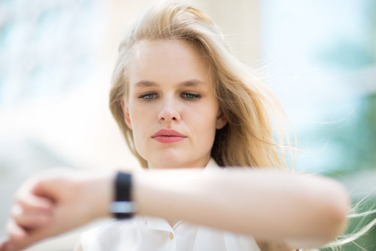 eine blonde frau schaut auf ihre uhr