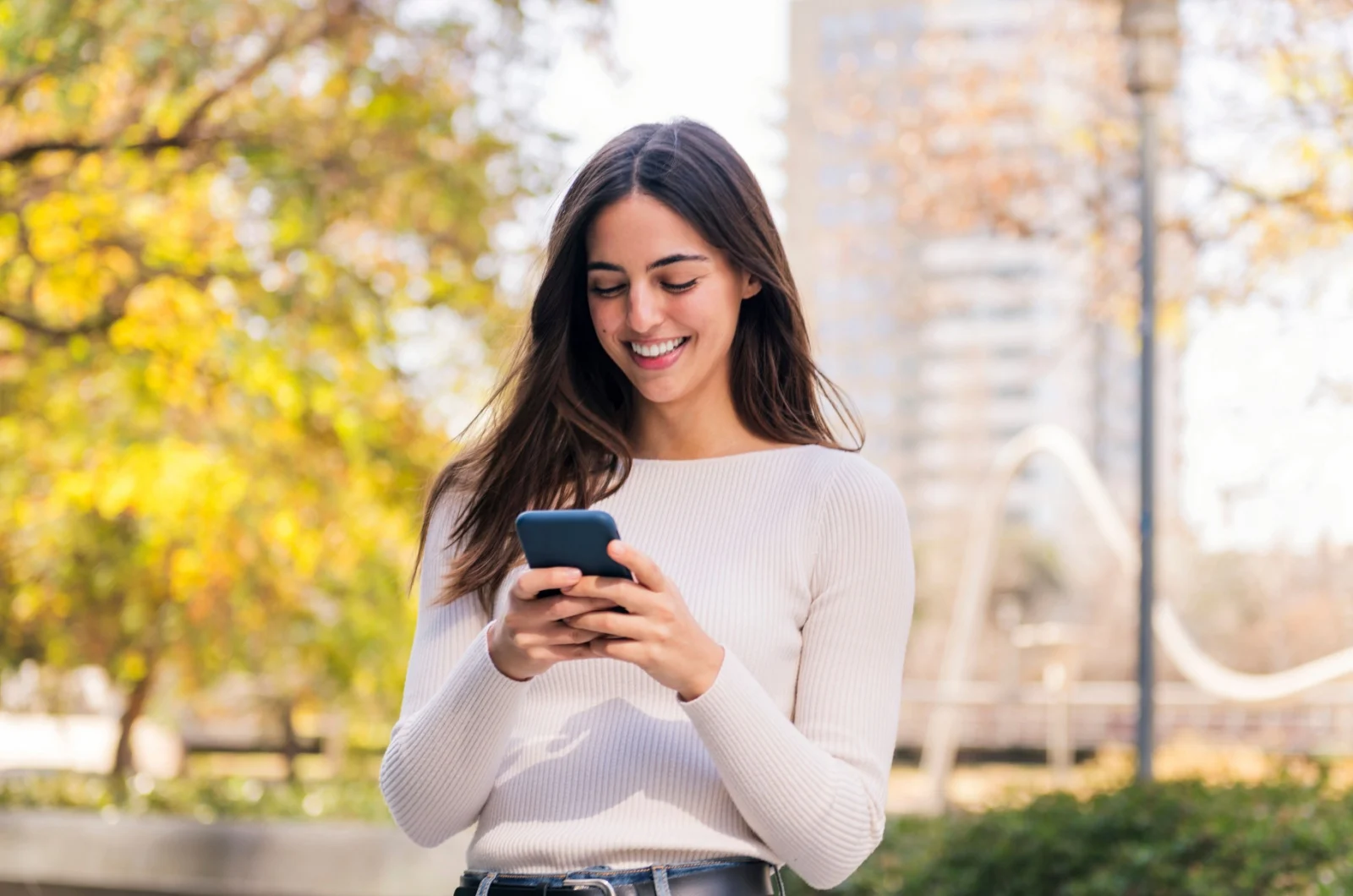 Frau laechelt und haelt ein Telefon