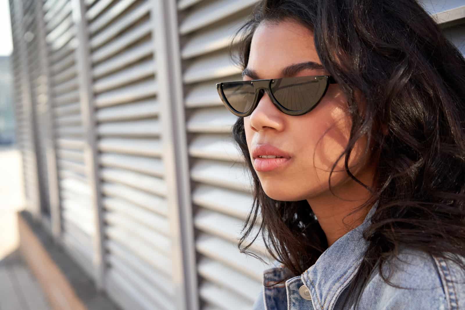 Frau mit stilvoller Sonnenbrille steht auf der Straße der Stadt