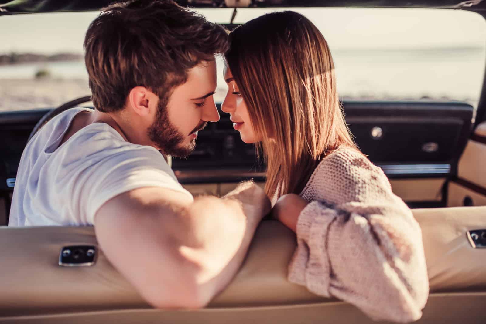 Romantisches Paar sitzt im grünen Retro-Auto am Strand