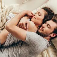 Schönes glückliches junges Paar, das sich beim Schlafen auf dem Bett umarmt