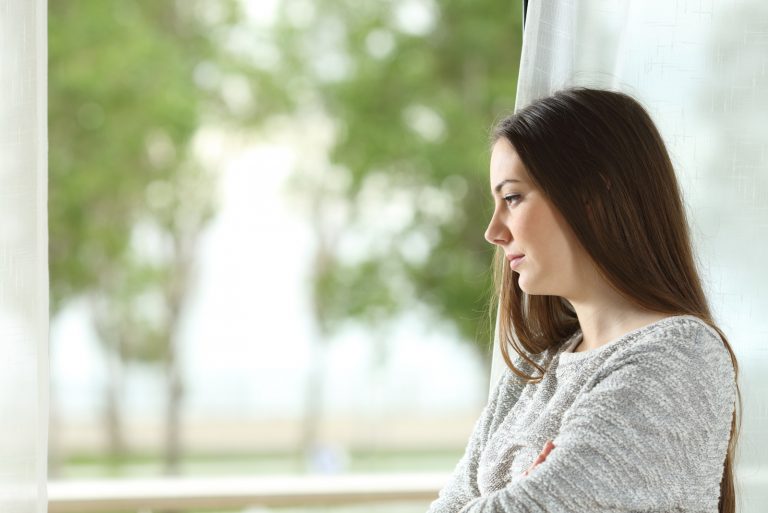 Frau, die zu Hause durch ein Fenster nach draußen schaut