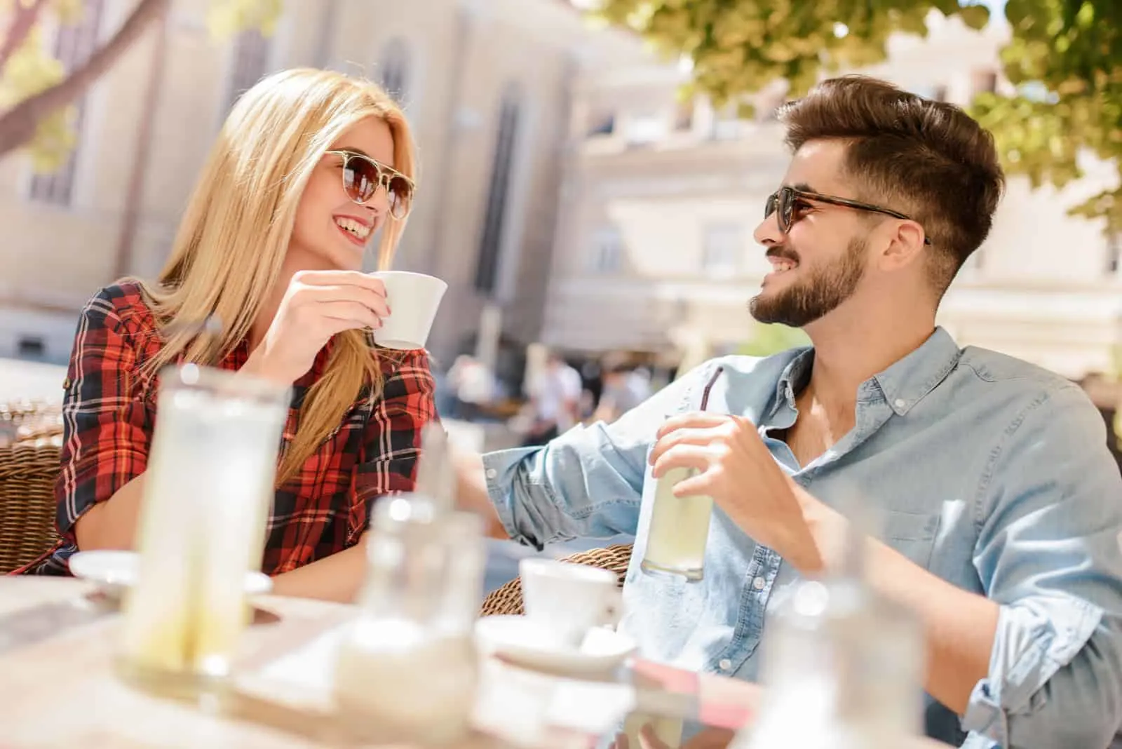 ein Mann und eine Frau sitzen draußen, trinken Kaffee und unterhalten sich