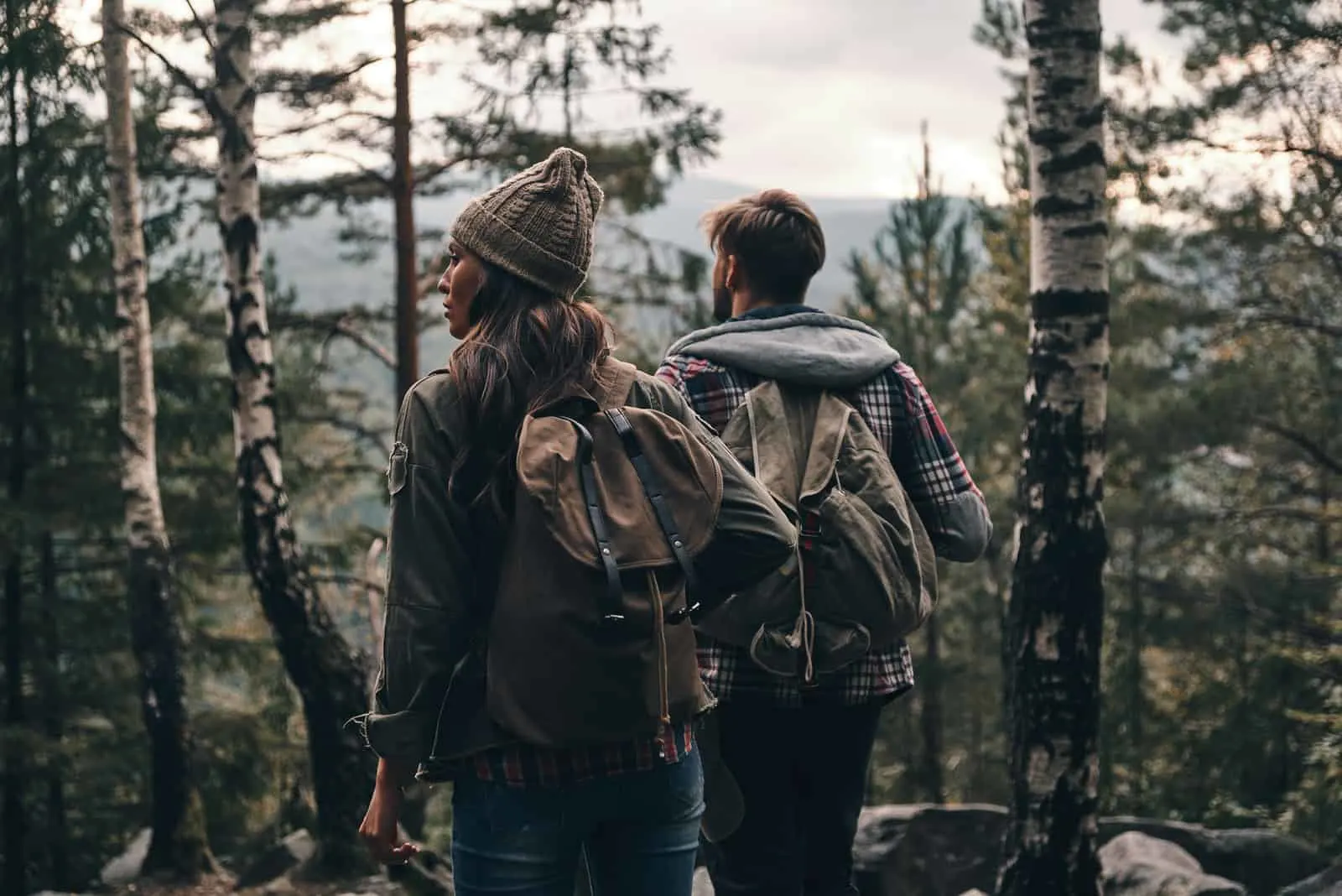 junges Paar, das beim gemeinsamen Wandern im Wald steht und wegschaut