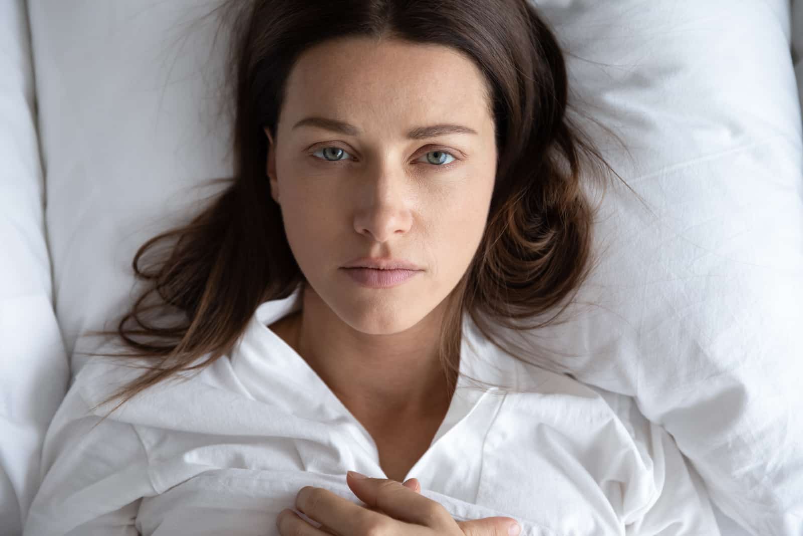 verärgerte und traurige frau, die im bett liegt