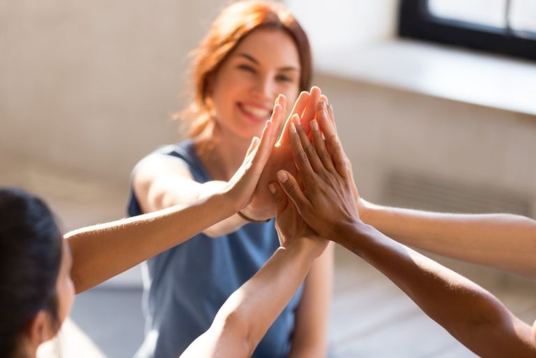 Fröhliche, vielfältige junge Mädchen, die zusammen im Sportstudio sitzen, bevor sie mit dem Training beginnen, fühlen sich glücklich und gesund, Nahaufnahme der Hände.