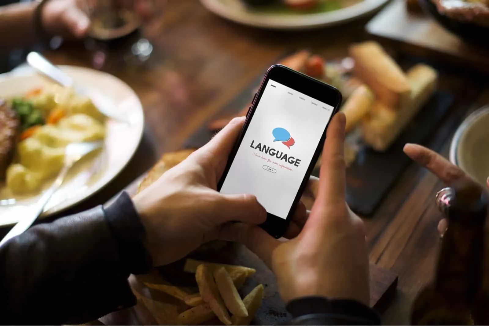 App zur grafischen Sprachübersetzung auf dem Smartphone, das ein Mann beim Abendessen hält