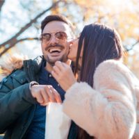 Romantisches Paar, das auf der Bank sitzt und schöne Momente des Glücks und der Freude im Herbstpark hat