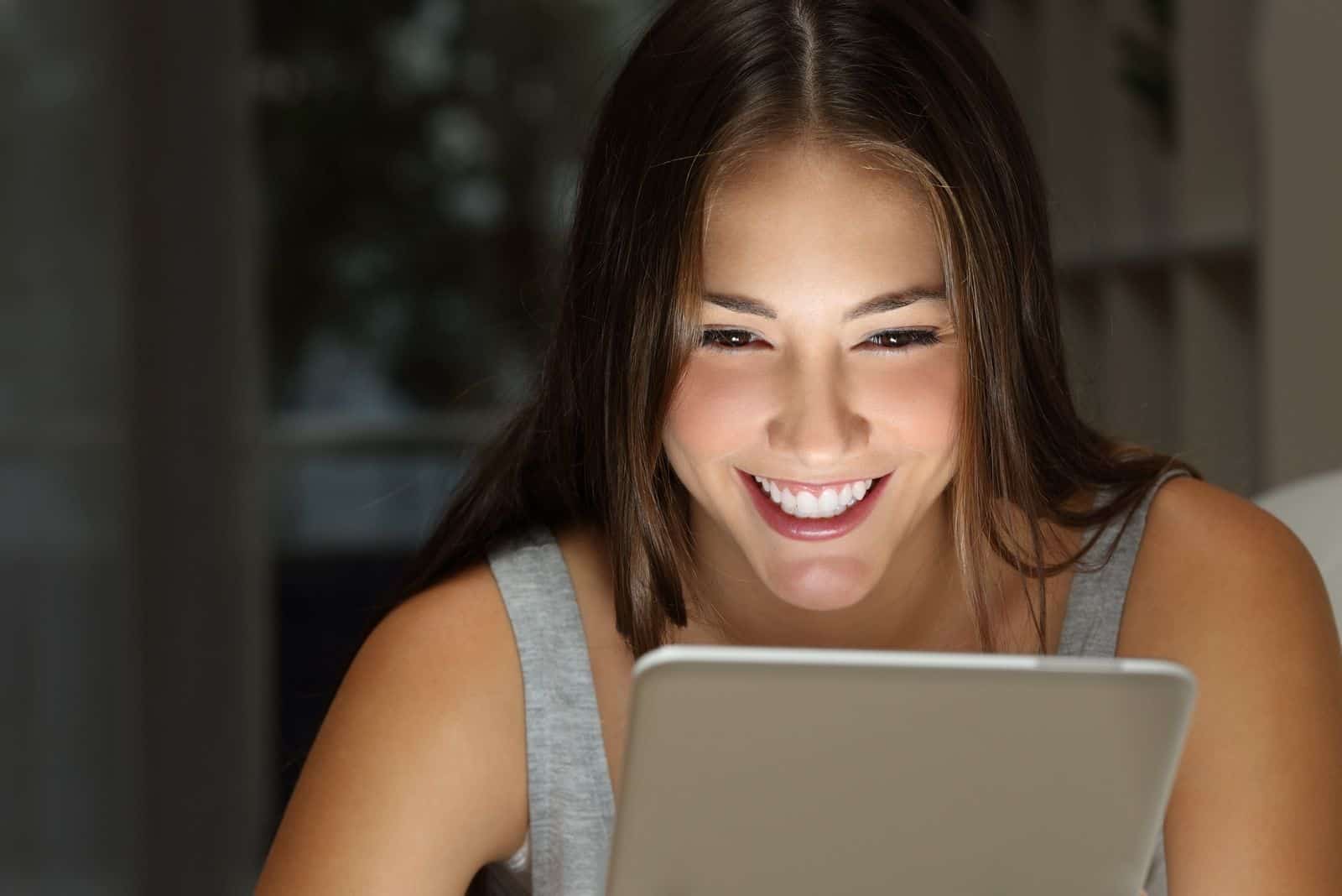 Frau lacht nachts Betrachten Sie ihre sozialen Medien über die Registerkarte in Nahaufnahme