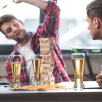 junge Männer trinken Bier und spielen Jenga-Spiel