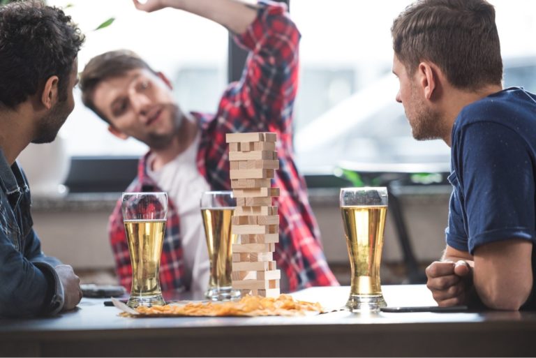 junge Männer trinken Bier und spielen Jenga-Spiel