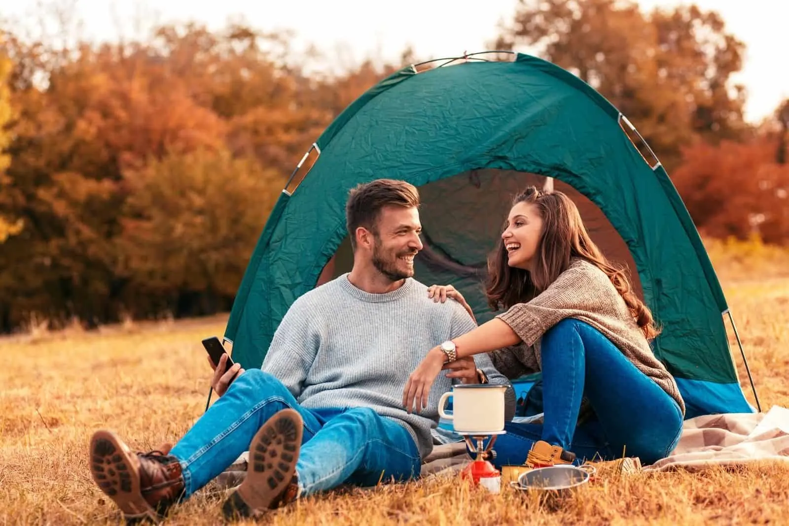 Junges Paar im Campingurlaub Sitzen und Lachen am Campingzelt