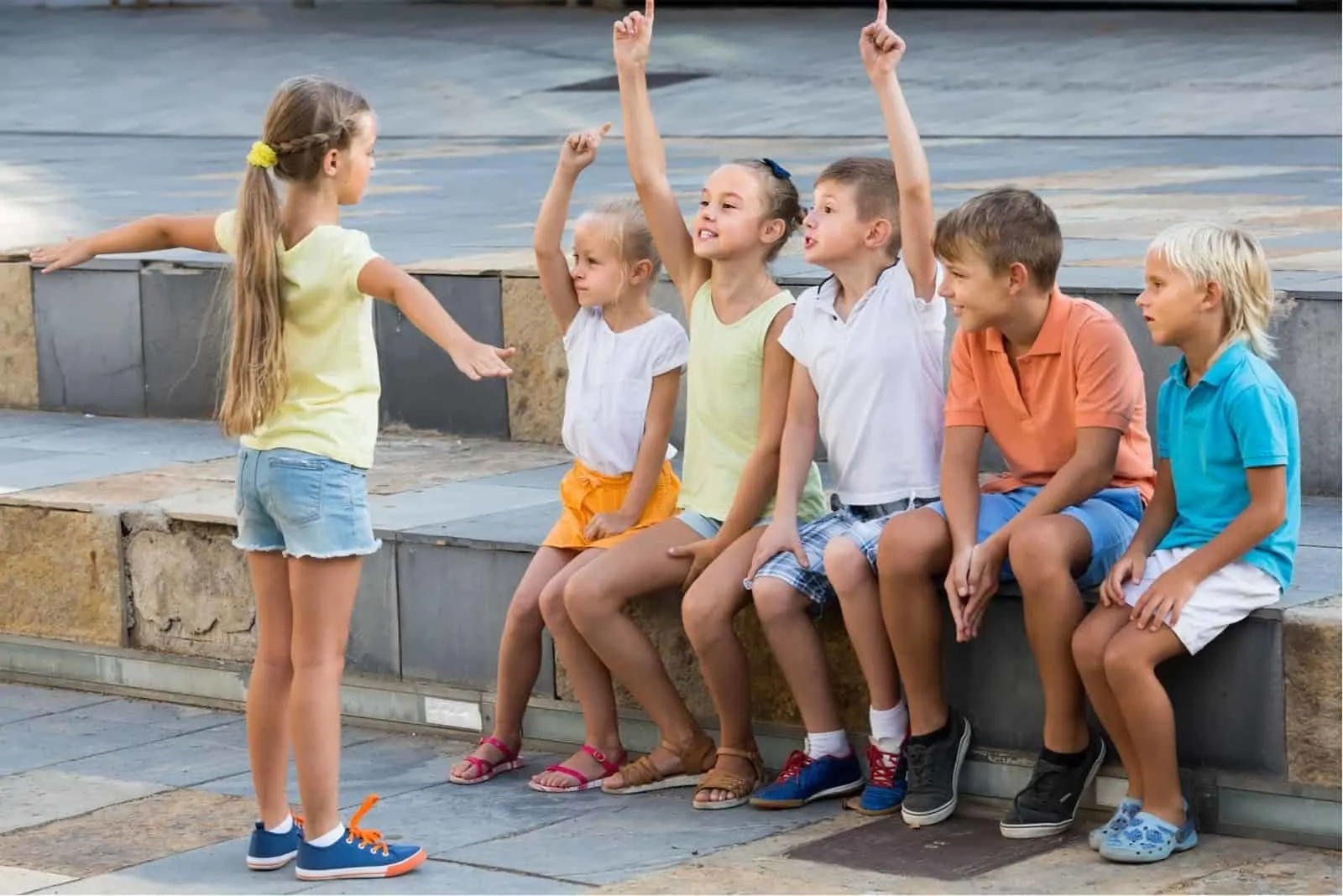 Kinder im Schulalter Spielen im Freien mit einem Lautsprecher vor fünf Kindern