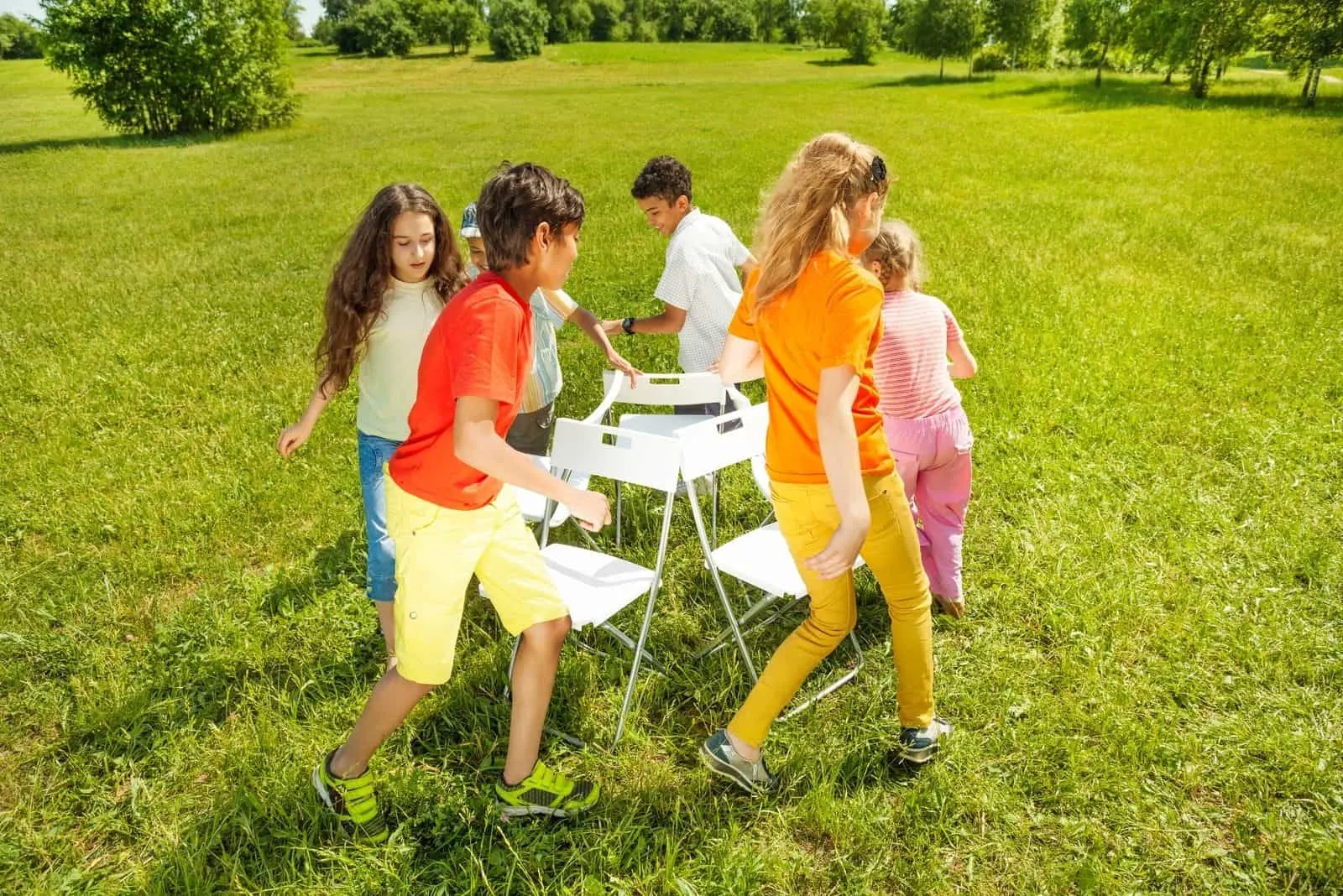 Kinder laufen um die Stühle herum Musikstuhl im Freien spielen