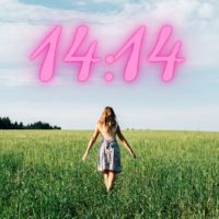 Junge Frau im Weizenfeld in Ansicht von hinten mit 14:14 in den Himmel geschrieben