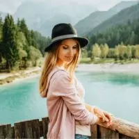 Junge schöne Frau mit Hut, die allein auf der Holzbrücke mit Blick auf die schöne Natur steht