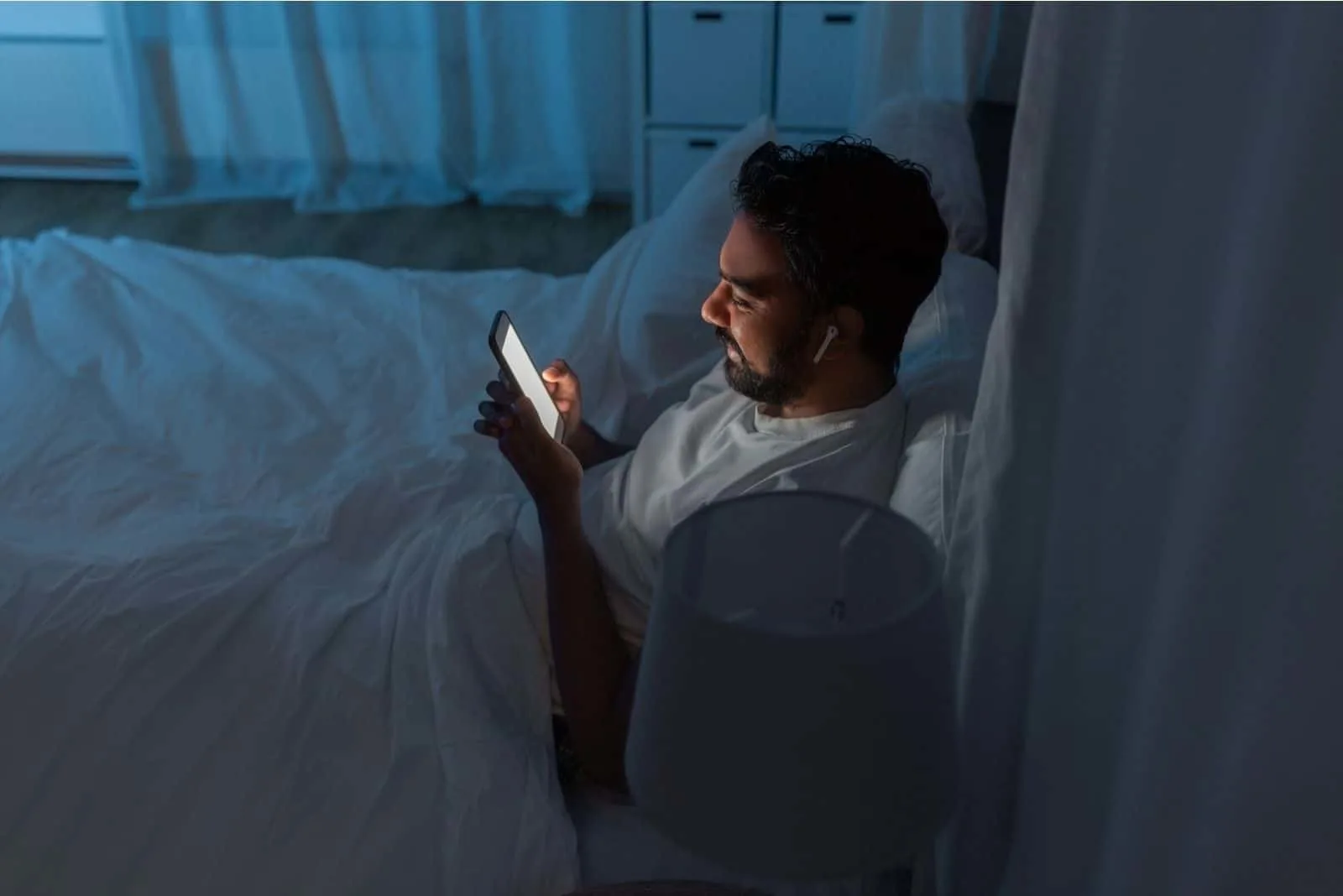 Mann im Bett. Verwenden von Technologie oder Telefon, bevor Sie anschlafen