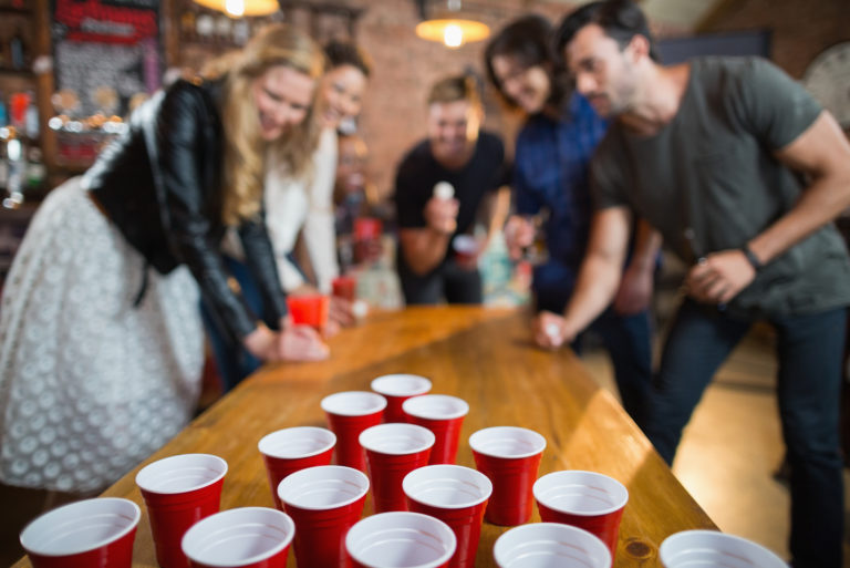 Freunde, die Bierpong-Spiel auf dem Tisch in der Bar genießen