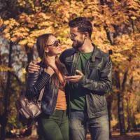 ein lächelnder Mann und eine Frau, die durch den Park gehen